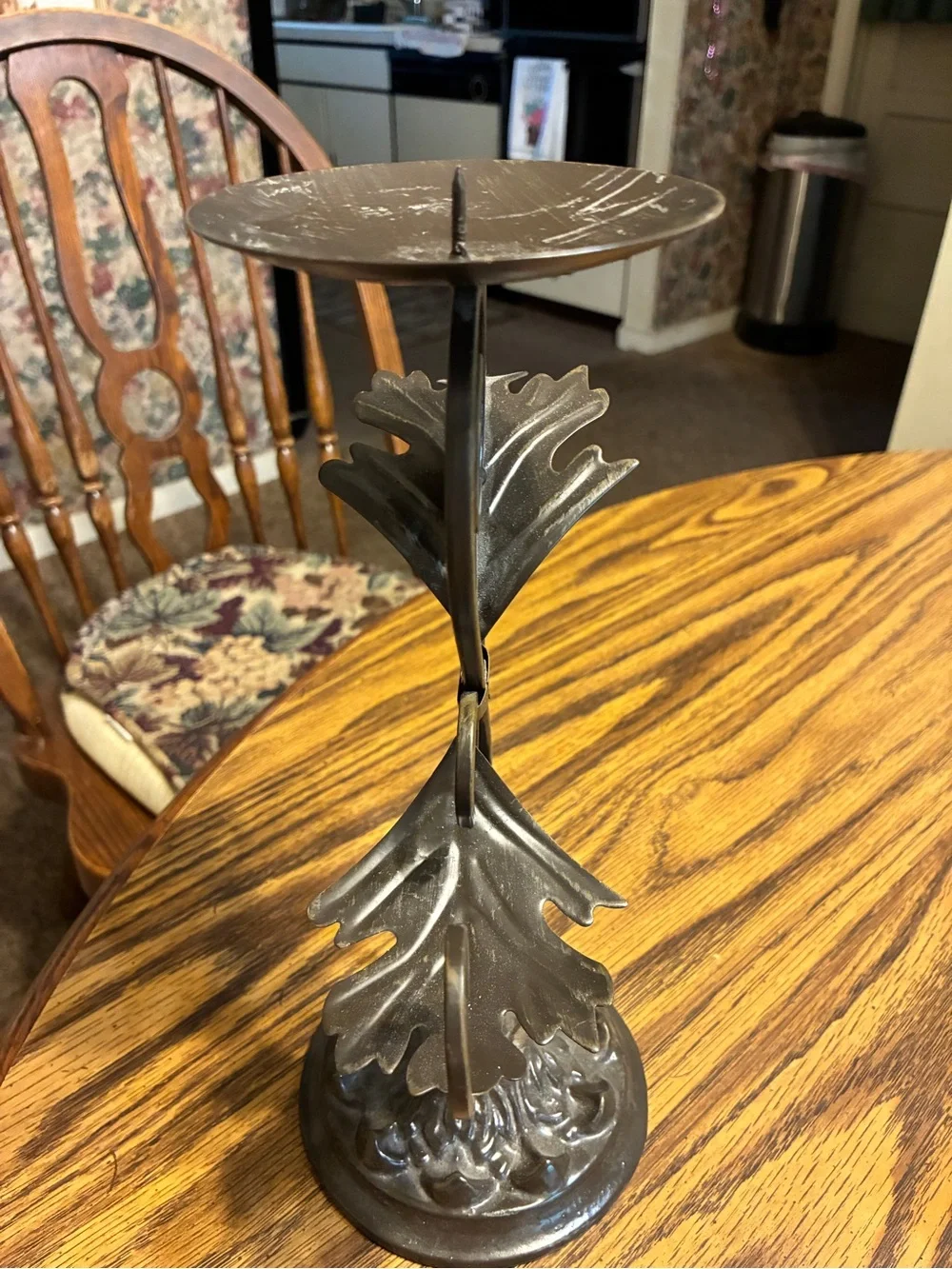 vintage-style brown cast iron pillar candle holder features an ornate leaf